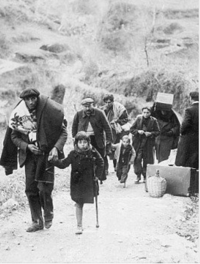 Familles de réfugiés de la Retirada marchant sur une route de montagne avec leurs bagages.